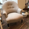 French vintage tub chair covered in Taupe linen with a buttoned back, black turned legs and castors. Late 19th C.